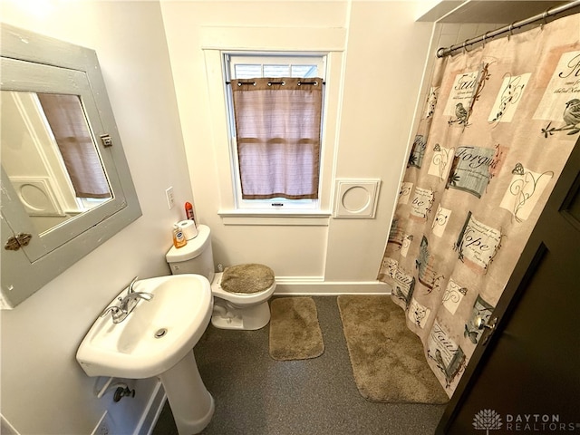 bathroom with walk in shower, sink, and toilet