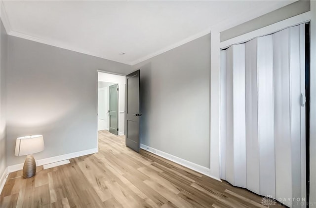 unfurnished bedroom featuring light hardwood / wood-style floors, a closet, and crown molding