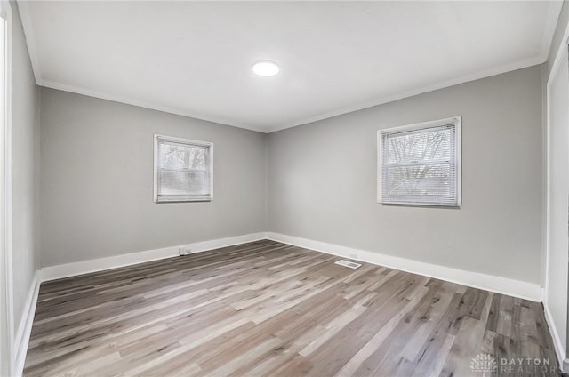 unfurnished room featuring light wood-type flooring, a wealth of natural light, and crown molding