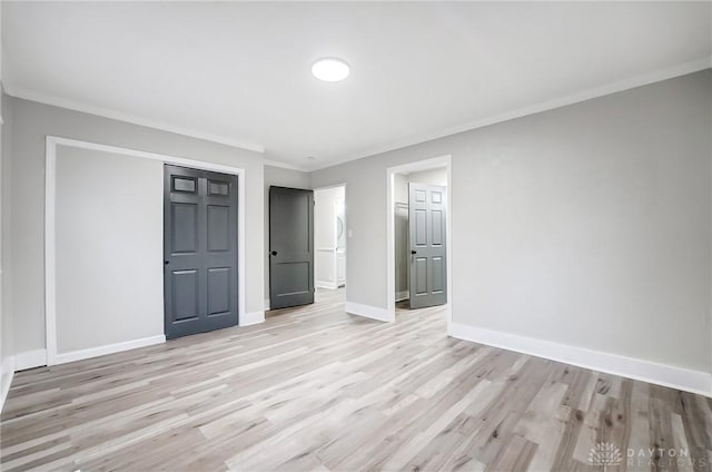 unfurnished bedroom with light hardwood / wood-style flooring, crown molding, and a closet