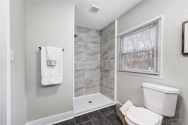 bathroom with tiled shower, tile patterned floors, and toilet