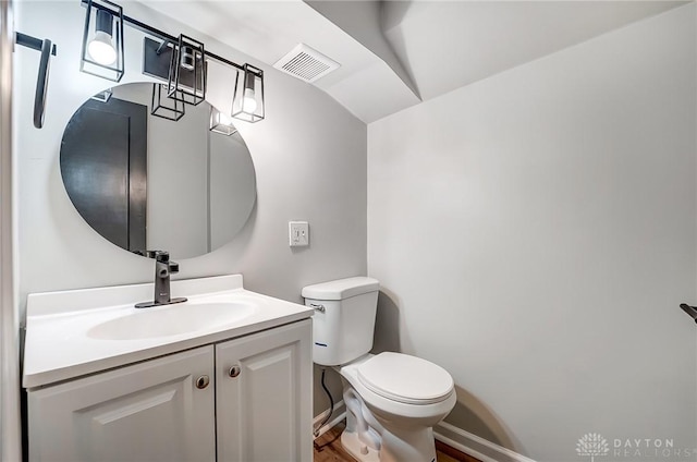 bathroom with vanity, toilet, and lofted ceiling