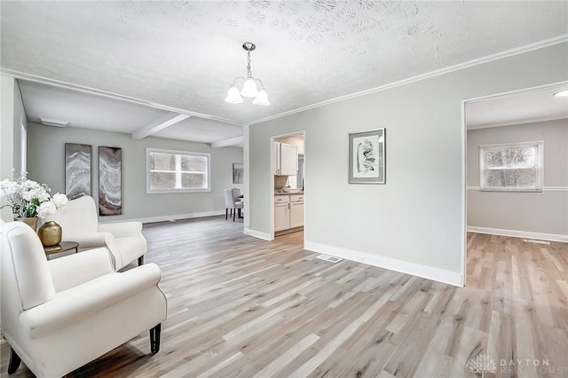 unfurnished living room featuring beamed ceiling, ornamental molding, a textured ceiling, and light wood-type flooring