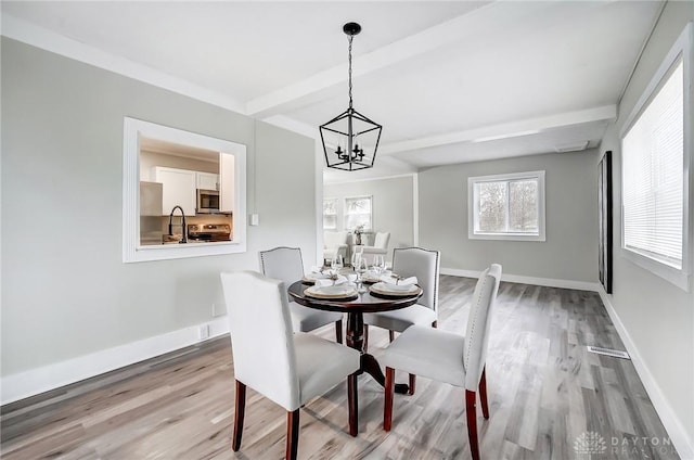 dining area featuring wood-type flooring, a notable chandelier, and sink