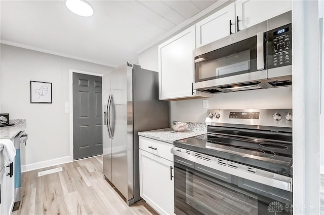 kitchen with light stone countertops, stainless steel appliances, white cabinetry, and light hardwood / wood-style flooring