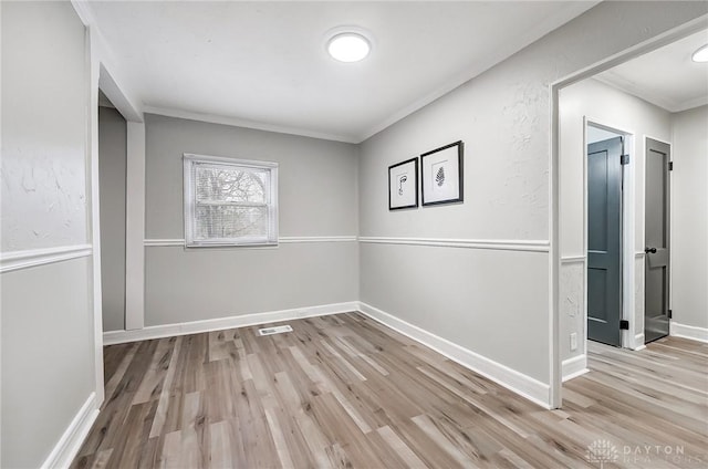 empty room featuring light hardwood / wood-style flooring and ornamental molding