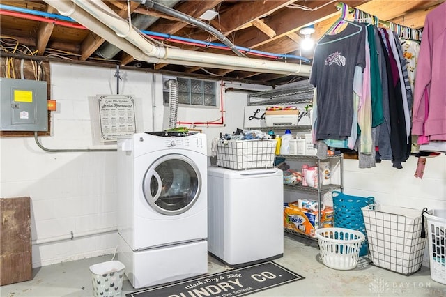 washroom with concrete block wall, laundry area, electric panel, and independent washer and dryer