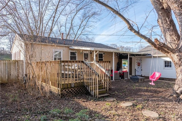 back of property with fence and a wooden deck