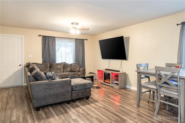 living area featuring ceiling fan, baseboards, and wood finished floors