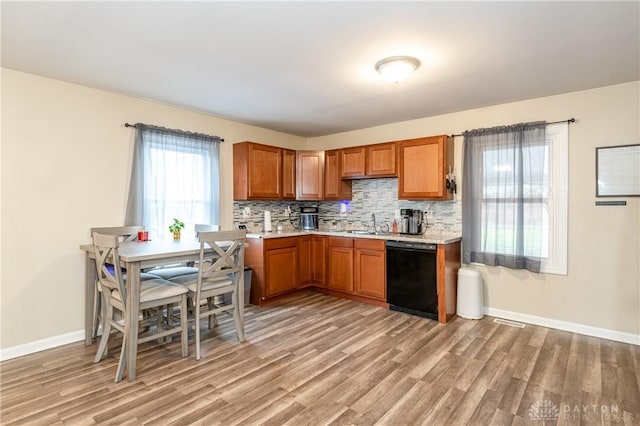 kitchen with black dishwasher, brown cabinets, light countertops, decorative backsplash, and light wood-style floors