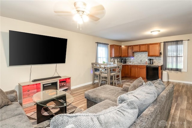 living area featuring baseboards, ceiling fan, and light wood-style floors