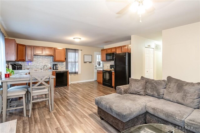 living room featuring ceiling fan, light hardwood / wood-style floors, and sink