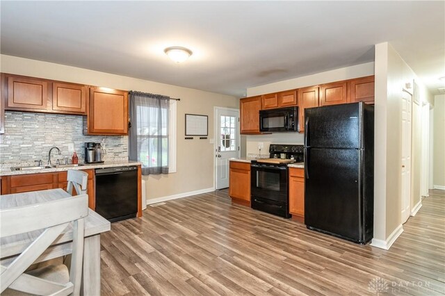 kitchen featuring tasteful backsplash, sink, black appliances, and light hardwood / wood-style floors