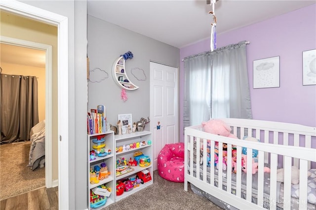 bedroom with a nursery area, carpet floors, and a closet