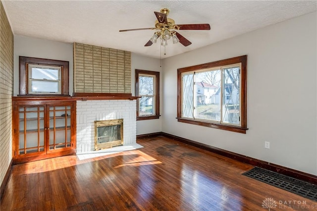 unfurnished living room featuring a fireplace, a textured ceiling, hardwood / wood-style flooring, and ceiling fan