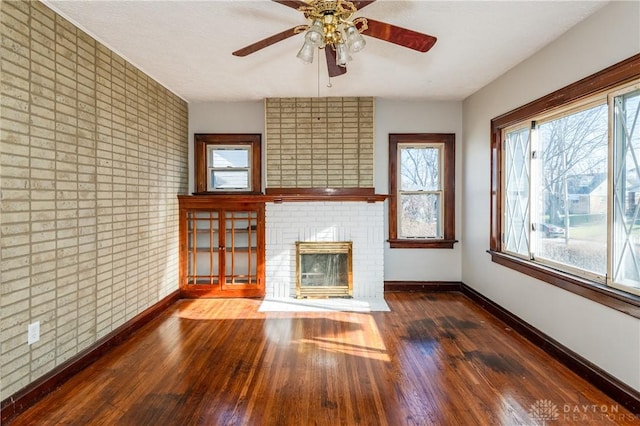 unfurnished living room with ceiling fan, dark wood-type flooring, and a brick fireplace