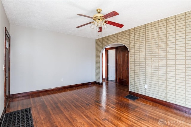 unfurnished room with ceiling fan, dark hardwood / wood-style flooring, and a textured ceiling