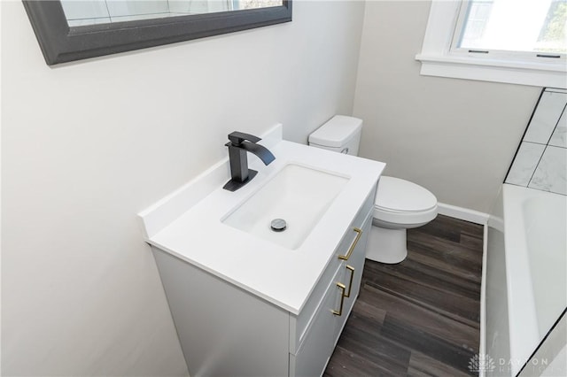 bathroom featuring hardwood / wood-style floors, vanity, a bathtub, and toilet