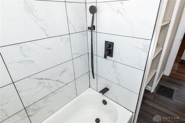 bathroom with wood-type flooring and tiled shower / bath