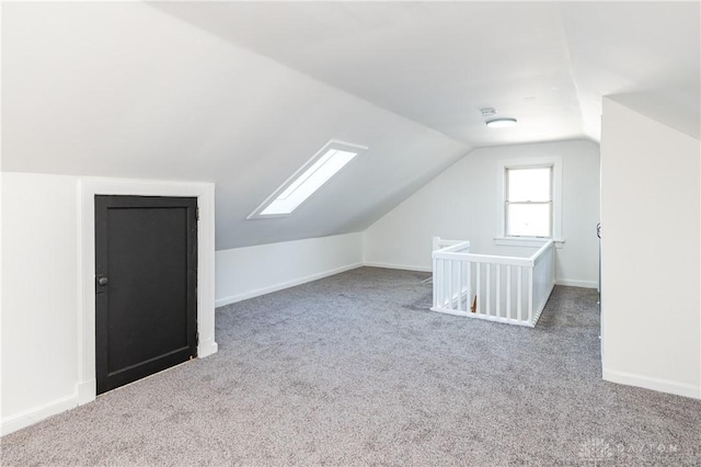 bonus room with vaulted ceiling with skylight and carpet flooring