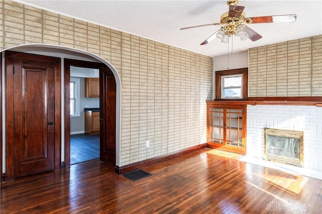 unfurnished living room featuring a textured ceiling, dark hardwood / wood-style floors, ceiling fan, and a fireplace