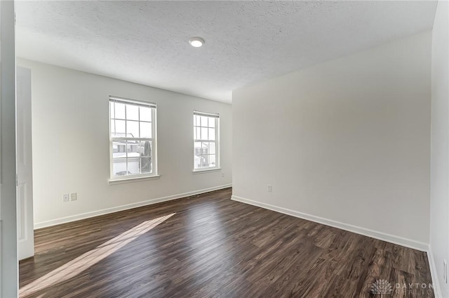 unfurnished room with a textured ceiling and dark hardwood / wood-style flooring