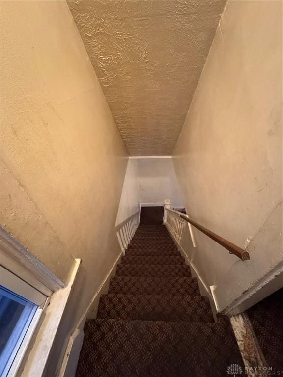 stairs with carpet flooring and a textured ceiling