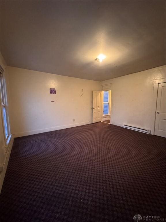 carpeted spare room featuring baseboard heating