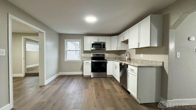 kitchen with appliances with stainless steel finishes, white cabinetry, and sink