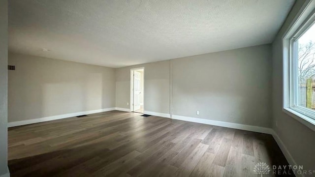 spare room with dark hardwood / wood-style floors and a textured ceiling