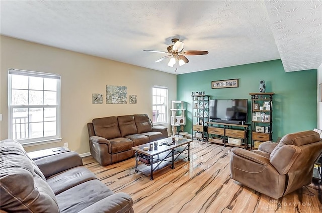 living room with ceiling fan, a textured ceiling, and light wood-type flooring