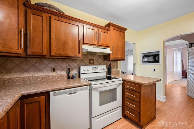 kitchen featuring white appliances, light hardwood / wood-style flooring, decorative backsplash, plenty of natural light, and kitchen peninsula