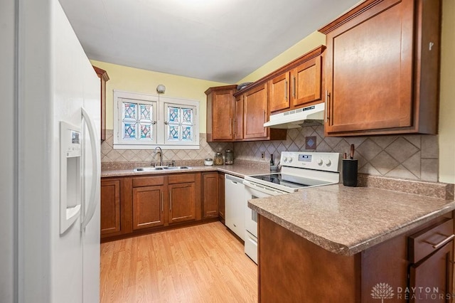 kitchen with sink, light hardwood / wood-style flooring, backsplash, pendant lighting, and white appliances