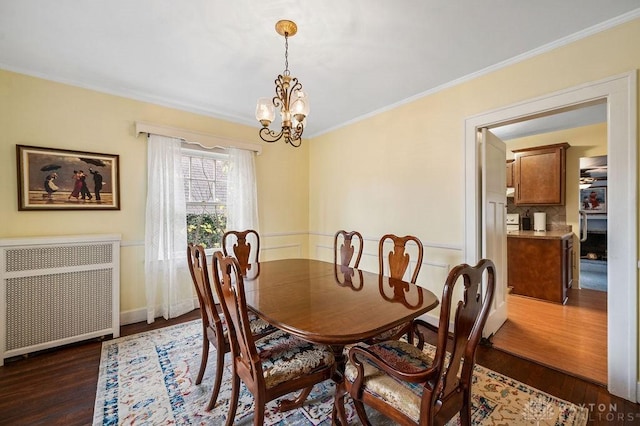 dining space with radiator, ornamental molding, dark wood-type flooring, and a notable chandelier