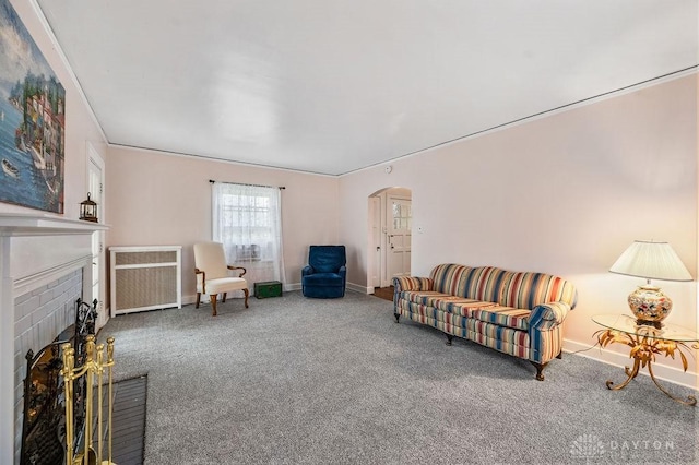 living room featuring radiator heating unit, carpet flooring, a fireplace, and ornamental molding