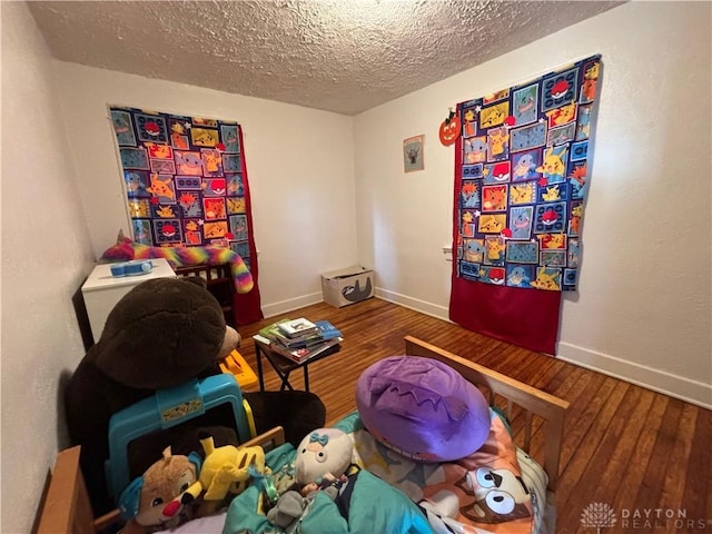 playroom featuring wood-type flooring and a textured ceiling