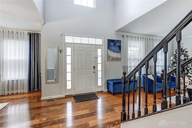 entrance foyer featuring a healthy amount of sunlight, wood-type flooring, and a high ceiling