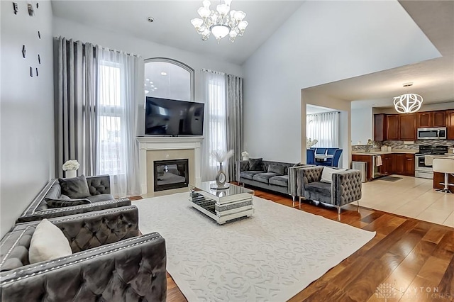 living room featuring dark hardwood / wood-style flooring, a healthy amount of sunlight, high vaulted ceiling, and a chandelier