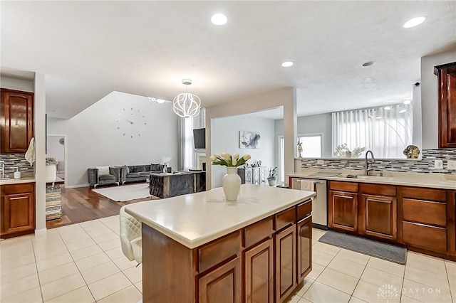 kitchen featuring a kitchen island, tasteful backsplash, dishwasher, sink, and light tile patterned floors