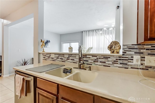 kitchen with tasteful backsplash, light tile patterned flooring, sink, and stainless steel dishwasher