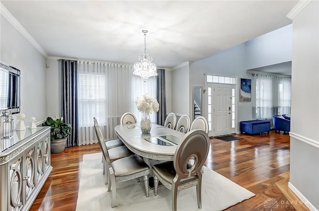 dining area with a notable chandelier, ornamental molding, and dark hardwood / wood-style floors