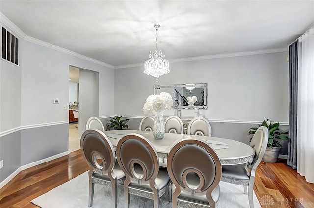 dining area featuring ornamental molding, hardwood / wood-style floors, and a notable chandelier