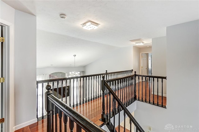 hallway with an inviting chandelier and wood-type flooring