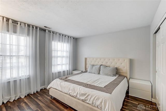 bedroom with dark wood-type flooring, a textured ceiling, and a closet