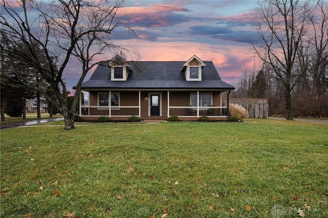 new england style home featuring covered porch and a lawn