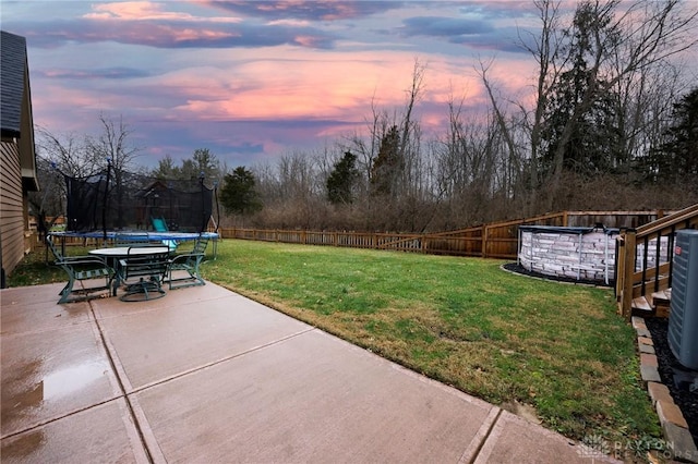 yard at dusk with a patio area and a trampoline