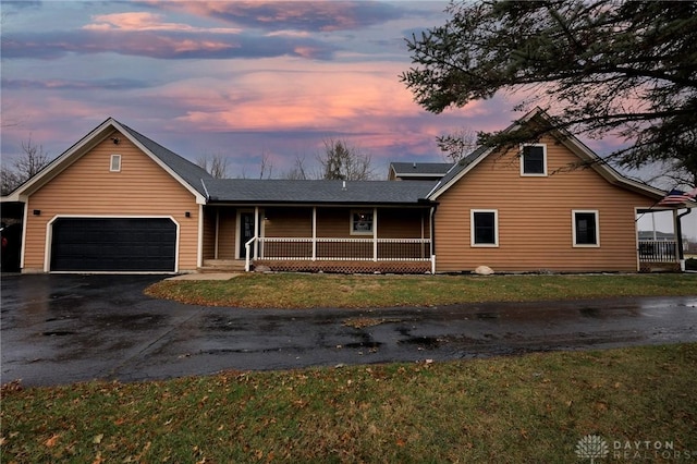 view of front of house featuring a porch, a garage, and a lawn