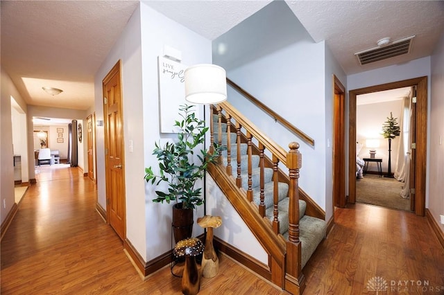 staircase with wood-type flooring and a textured ceiling