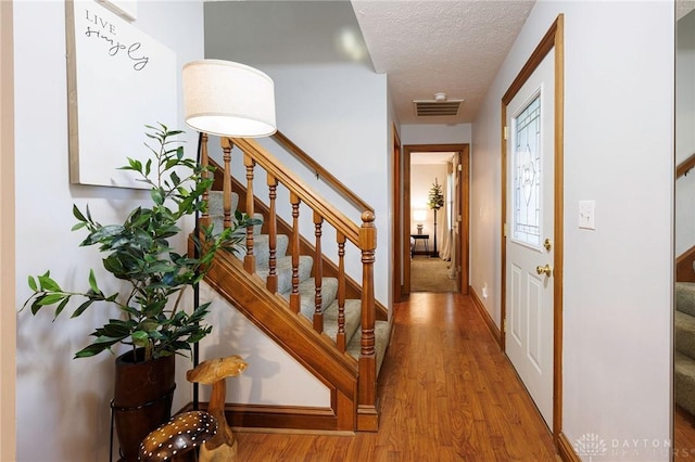 hall with light wood-type flooring and a textured ceiling