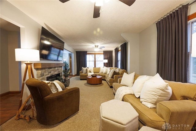 living room featuring a fireplace, wood-type flooring, a textured ceiling, and ceiling fan